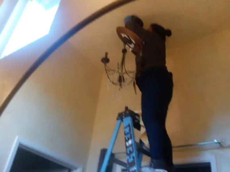 Electrician installing a chandelier in a Walden residence